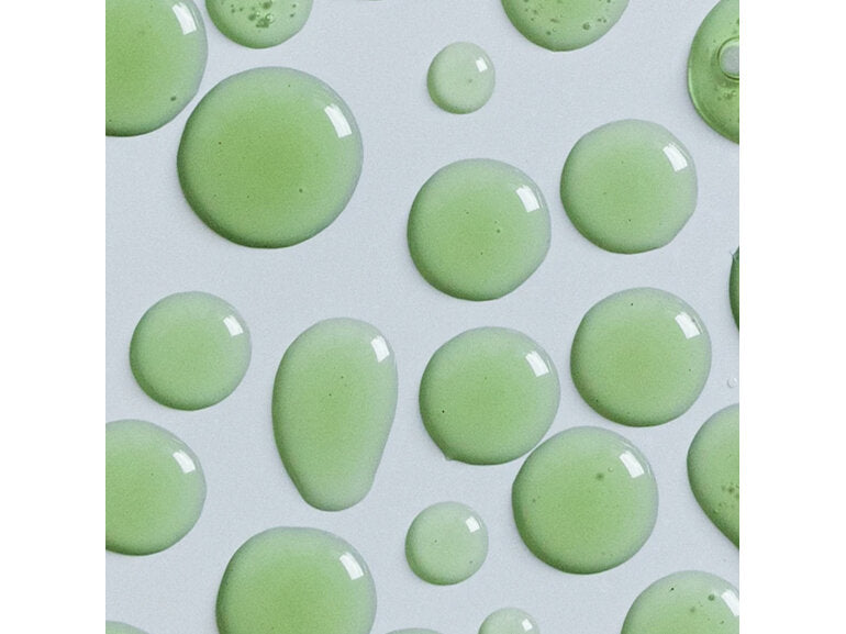 Close-up of green serum droplets on a white surface, representing the texture of ECO BY SONYA SERUM OF CLEAR 30ML with smooth, glossy consistency.
