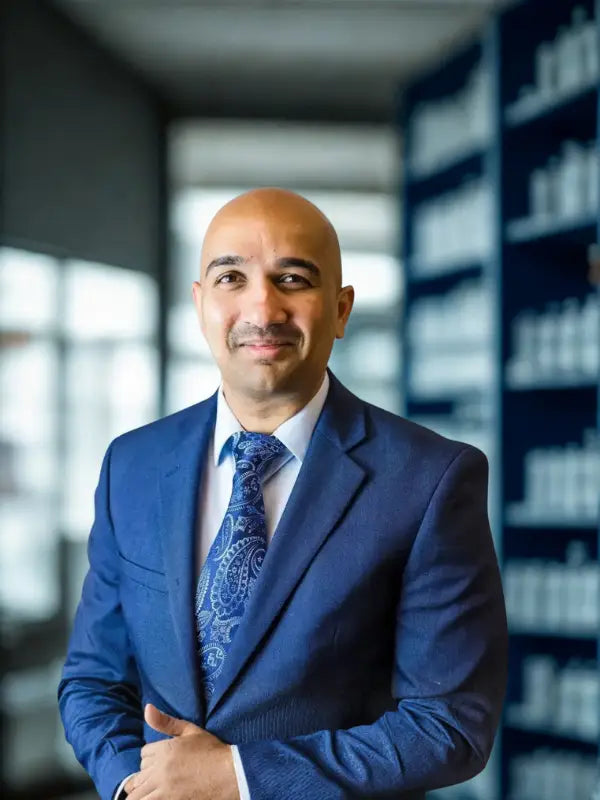 Shravan_Bolli is in a blue suit with a patterned tie standing in an office setting