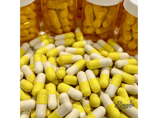 Close-up of yellow and white capsules scattered in front of several amber bottles, representing Bagga's Migraine Relief Capsules for expert medication support at Woden Compounding Pharmacy.