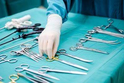 Surgeon's hand with surgical instruments on a teal table